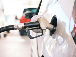 Gas pump nozzle in the fuel tank of a gray car, refuel