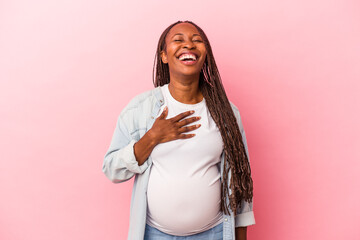 Young african american pregnant woman isolated on pink background laughs out loudly keeping hand on...