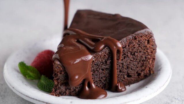 Pouring chocolate sauce on chocolate cake, closeup view. Delicious sweet cake slice