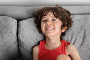 Portrait of young boy smiling on grey couch