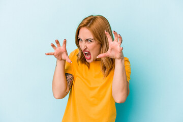 Young caucasian woman isolated on blue background upset screaming with tense hands.
