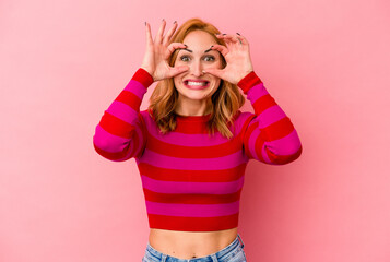 Young caucasian woman isolated on pink background keeping eyes opened to find a success opportunity.