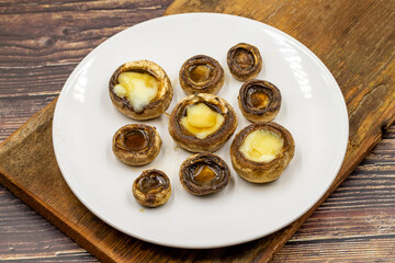 Baked mushrooms in a ceramic plate on a wooden background. Cultivated mushroom or portabello mushroom