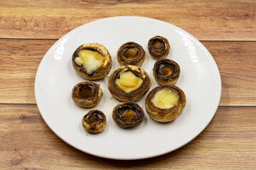 Baked mushrooms in a ceramic plate on a wooden background. Cultivated mushroom or portabello mushroom