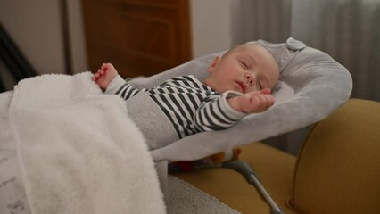 Adorable cute baby boy sleeping in a baby rocker