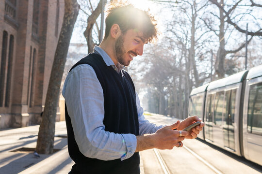 Hispanic man checking time on mobile phone in the tram station