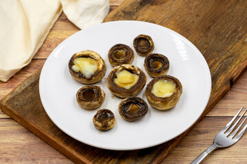 Baked mushrooms in a ceramic plate on a wooden background. Cultivated mushroom or portabello mushroom