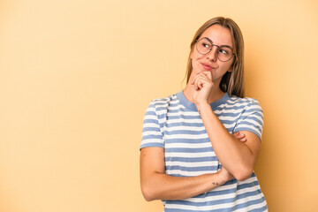 Young caucasian woman isolated on yellow background relaxed thinking about something looking at a copy space.