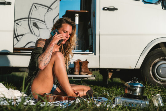 Woman talking on smartphone near camping van