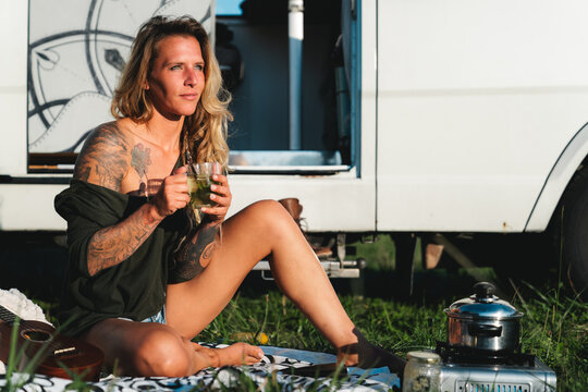 Woman drinking tea near camping van