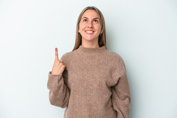 Young caucasian woman isolated on blue background indicates with both fore fingers up showing a...