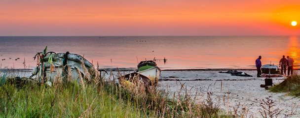 Naklejka na ściany i meble Coastal landscape with fishing boats and silhouettes of fishermen at dawn, Baltic Sea