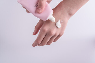 Close-up woman using hand cream, white background
