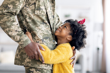 Happy Little Black Daughter Hugging Soldier Father In Military Uniform At Home