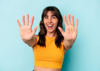 Young Argentinian woman isolated on blue background showing number ten with hands.