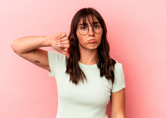 Young Argentinian woman isolated on pink background showing a dislike gesture, thumbs down....