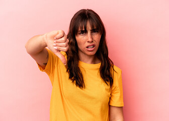 Young Argentinian woman isolated on pink background showing thumb down and expressing dislike.