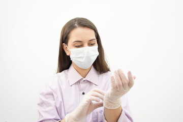 A swarthy white girl in a man's purple shirt, mask and gloves. The girl demonstrates how to properly wear gloves. Bacteria safety measures. Healthcare.