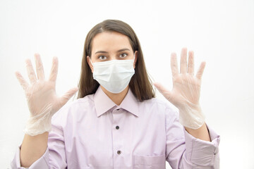 A swarthy white girl in a man's purple shirt, mask and gloves. The girl demonstrates how to properly wear gloves. Bacteria safety measures. Healthcare.
