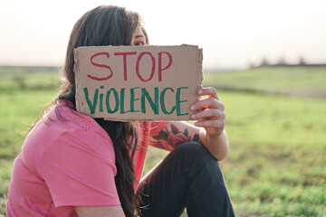 Woman covering her face with a STOP VIOLENCE carter