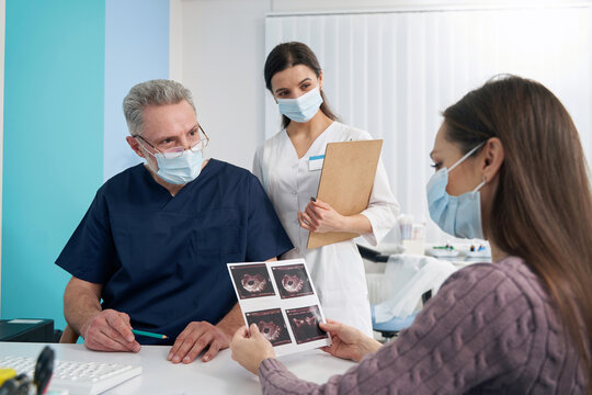 Focused woman looking at fetal ultrasound pictures after sonography