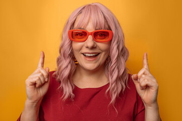 Portrait of attractive caucasian woman raises finger up, showing copy space, spreading information isolated on pink background