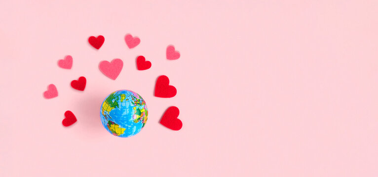 Global Valentines Day Concept - Spinning Earth with Hearts, isolated on beige pastel background. Love the Earth Planet. Globe Earth model with red heart. Top View, Flat Lay, Copy Space. Mock Up - Powered by Adobe