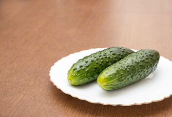 two green cucumbers lie on a white plate
