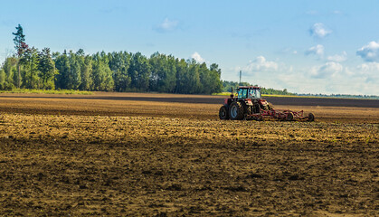 tractor plowing cereal field with sky with clouds. Copy space
