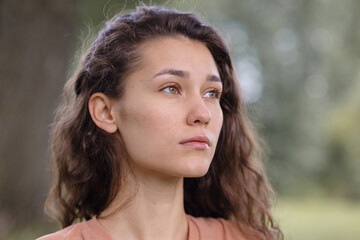 Fototapeta premium a woman with curly hair meditates in the park. yoga and meditation for mental and physical health. a beautiful young woman calmly looks thoughtfully and engages in breathing and spiritual practices