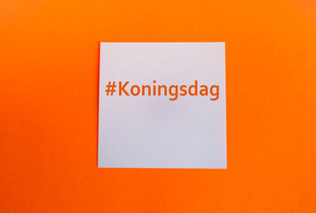 A template in the traditional colors of the King's Day celebration in the Netherlands. Orange background and a white paper square with the hashtag Koningsdag. Copy space