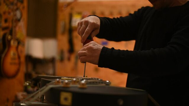 Electric guitar in repair service shop with a hands of a guitar luthier
