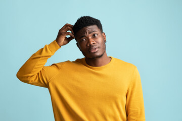 Confused black guy touching his head, blue background