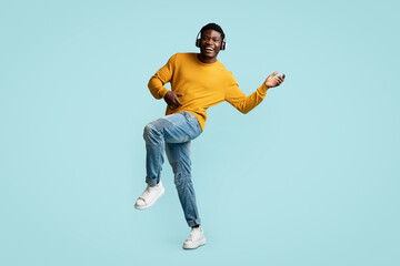 Carefree young black guy with wireless headset dancing
