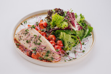 White fish dish with cherry tomatoes, lettuce, microgreens and sesame seeds