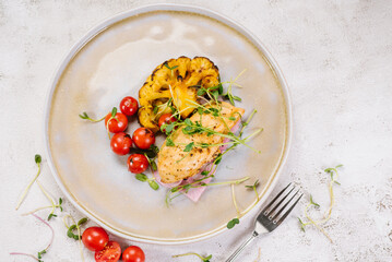 Dietary dish of chicken fillet with baked cauliflower, cherry tomatoes and microgreens