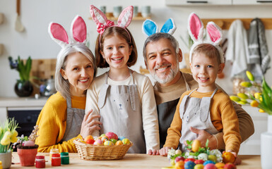 Family Easter traditions. Happy grandparents and kids in bunny ears headbands paint eggs together