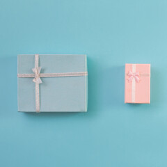 Gift boxes decorated with ribbon, small hearts on blue background, copy space. Flat lay, pink and blue present boxes, top view. Valentine or love, spring holidays, Christmas and birthday concept.