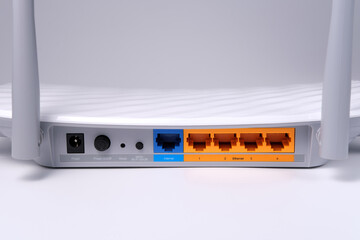The back side of a home wi-fi router with multi-colored RJ-45 connectors is isolated close-up on a...