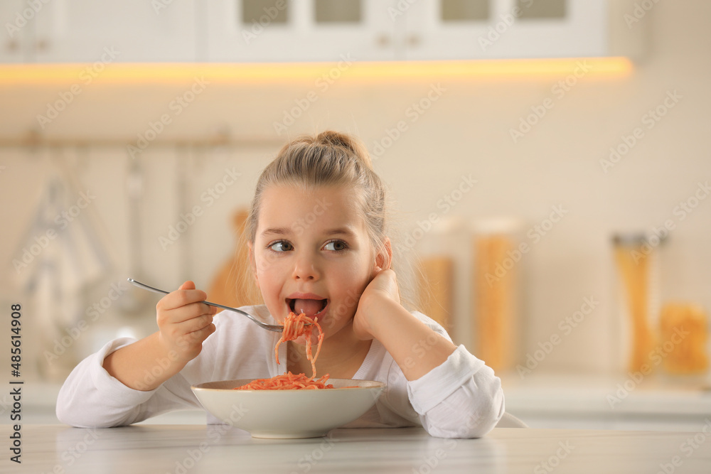 Canvas Prints Cute little girl eating tasty pasta at table in kitchen