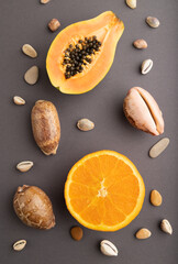 Ripe cut papaya and orange on gray pastel background. Top view, close up.