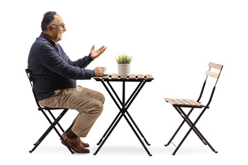 Profile shot of a mature man sitting in a cafe and gesturing with hand