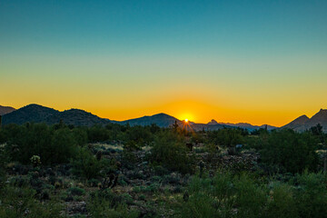 The sun peeks over the desert mountain at sunrise in Arizona