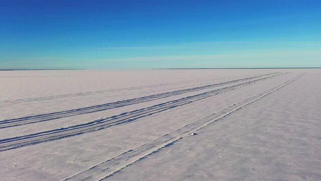 Aerial view of a empty ice crossing and snowy, frozen sea - circling, drone shot