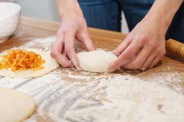 Girl preparing vegetarian pies with filling at home in the kitchen close-up. soft focus