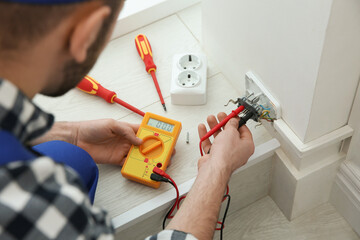 Electrician with tester checking voltage indoors, closeup