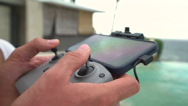 Close-up drone remote control in men's hands. Smartphone connected to the remote transmits a video image from the copter's camera.