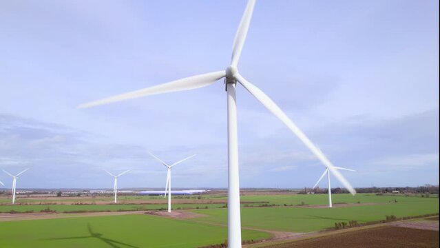 Low angle aerial shot looking up at spinning wind turbine at wind farm in UK