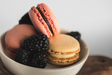 Bakery Still Life. Pastel Macarons. Raspberry Macarons with Fresh Raspberries in White Bowl on White Background.