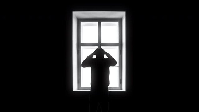 Depressed Man Silhouette Crying at Home Alone By Window. Lonely man silhouette depressed in front a window inside a house, zoom in